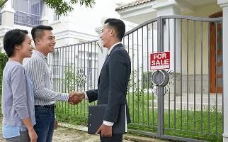 A real estate professional greeting two people outside a home